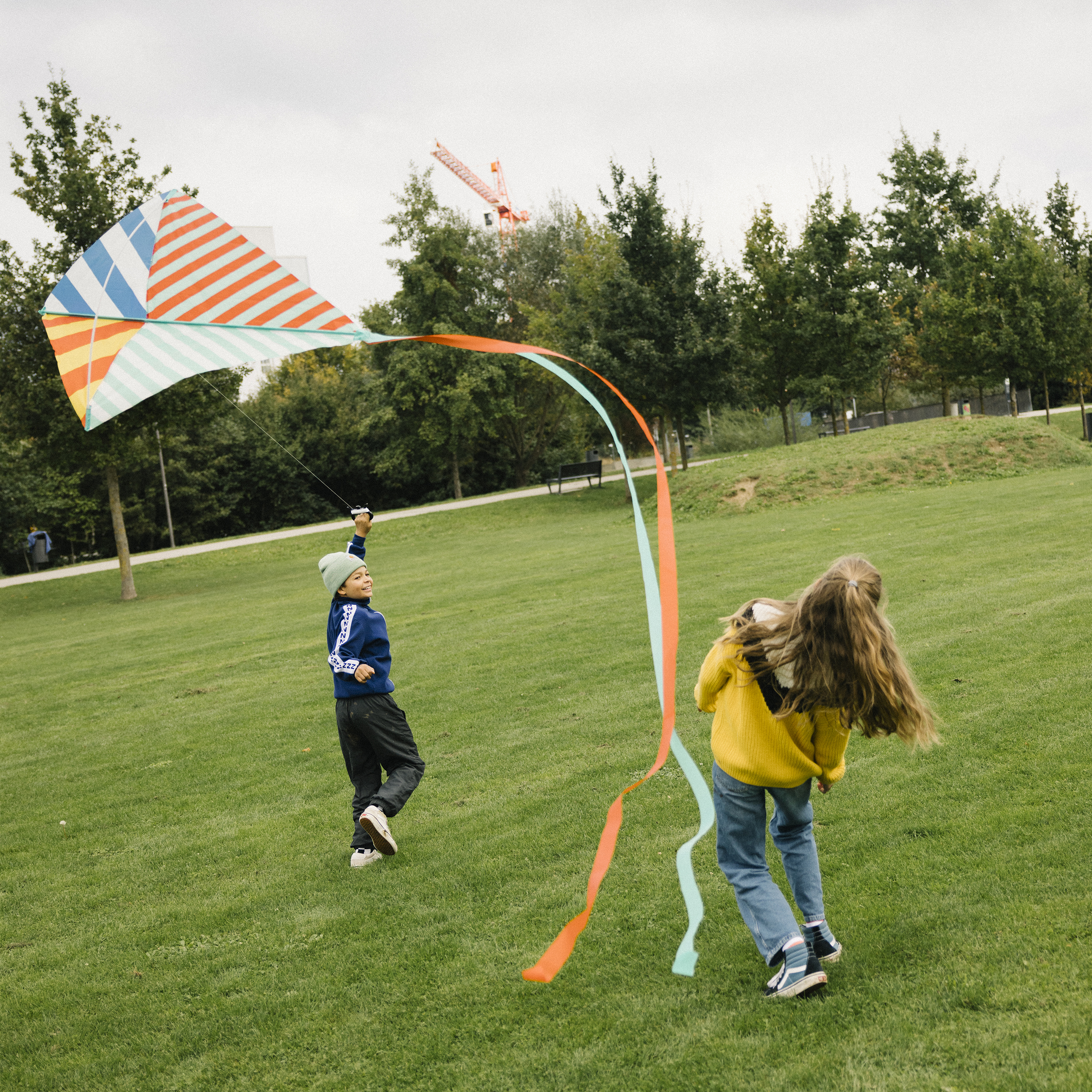 Two kids play with a kite in a meadow. 
