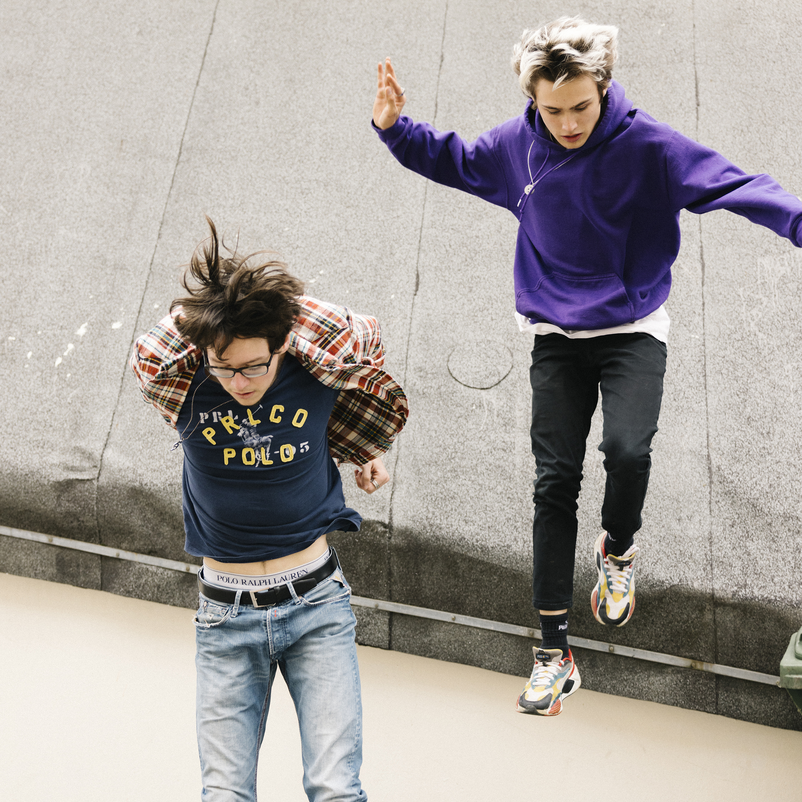 Two teenagers jump from a roof with a concentrated gaze.
