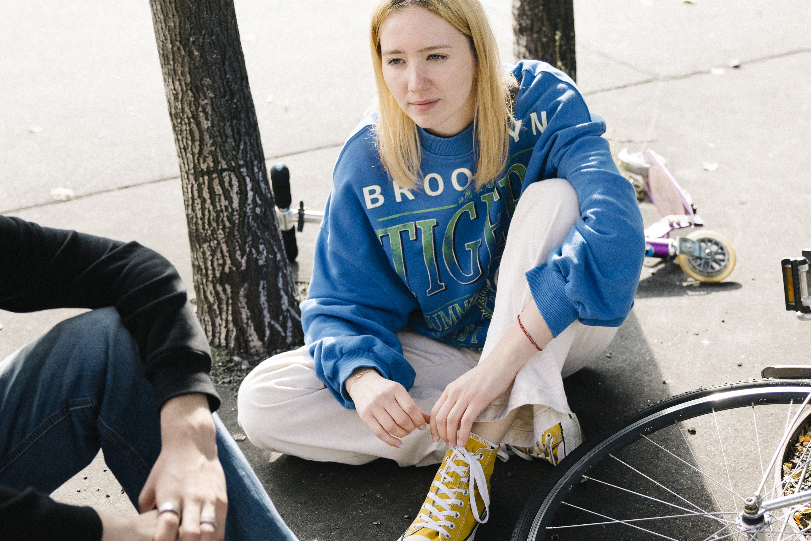 A teenager sits cross-legged on the floor and gazes dreamily into the distance.